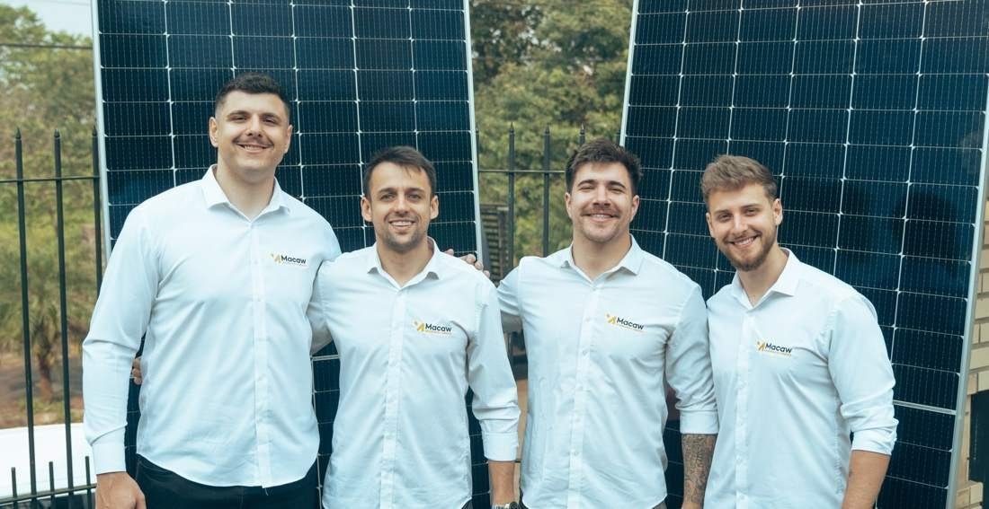 Equipe da Macaw em frente a módulos fotovoltaicos