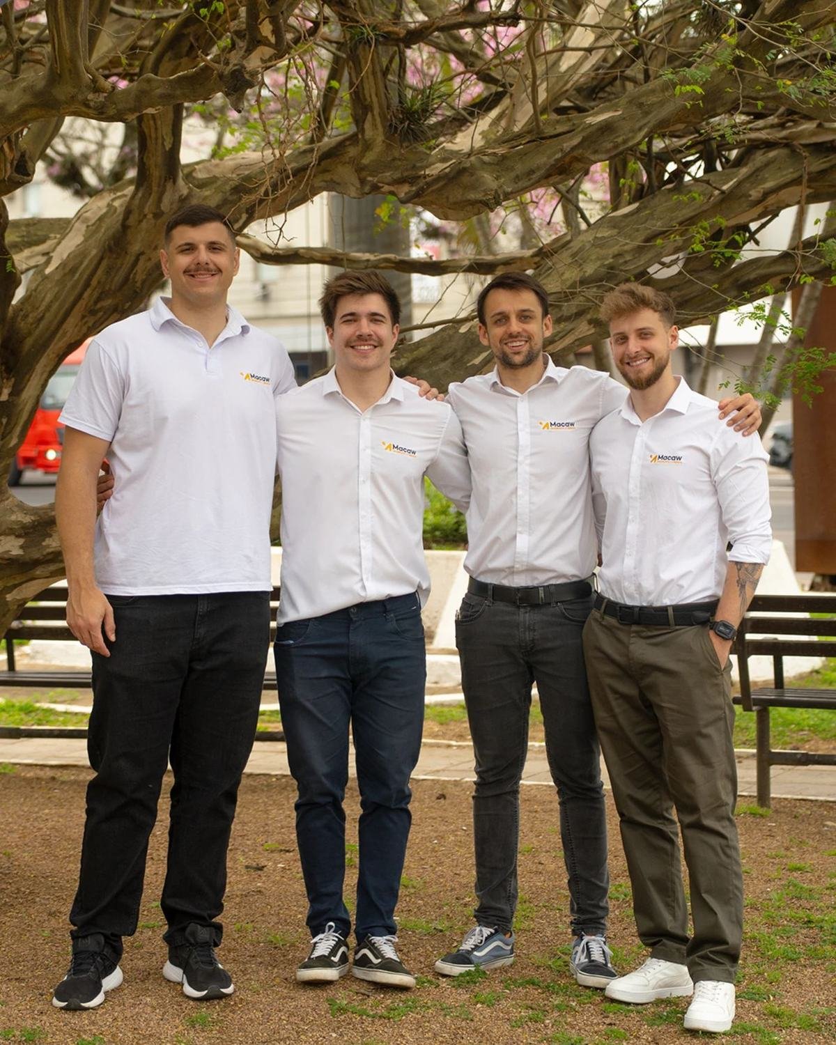 Equipe da Macaw em frente a módulos fotovoltaicos